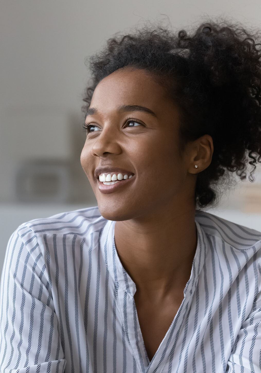 Smiling millennial African American woman relax in cozy own living room look in distance dreaming or visualizing. Happy young biracial female renter think or plan. Vision, visualization concept.